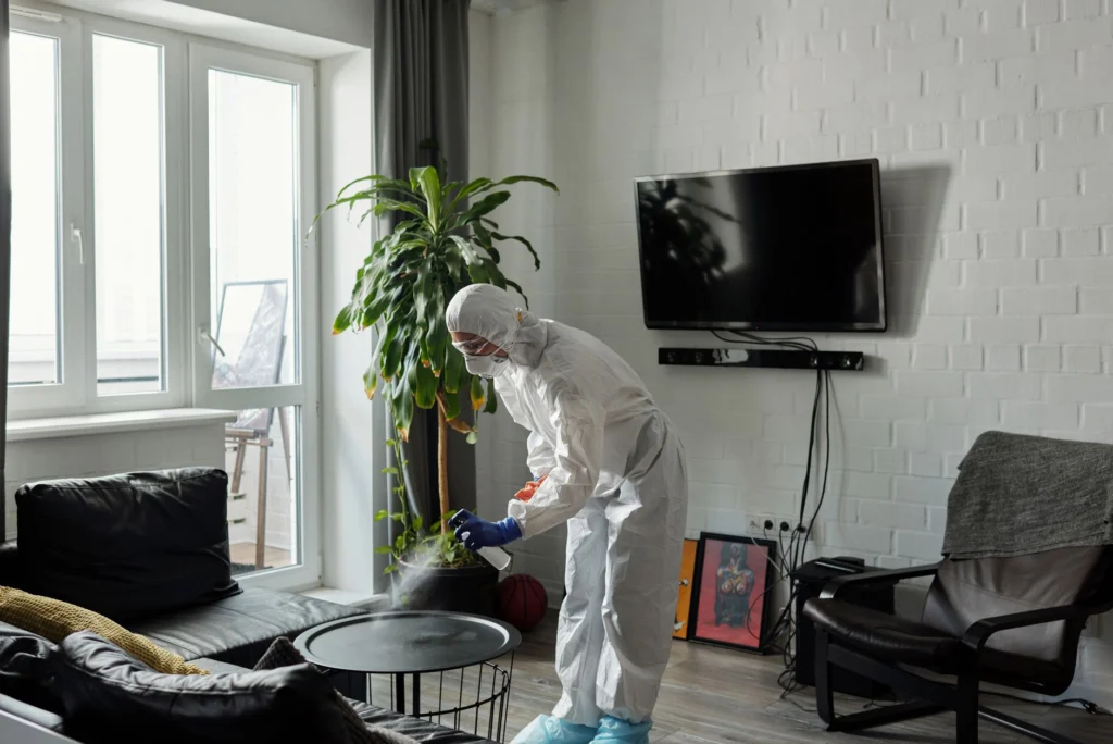 Technician in protective gear sanitizing a living room